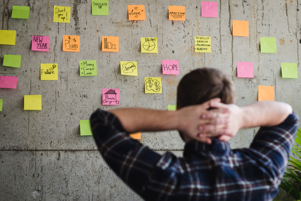 person looking over project post-it notes on wall