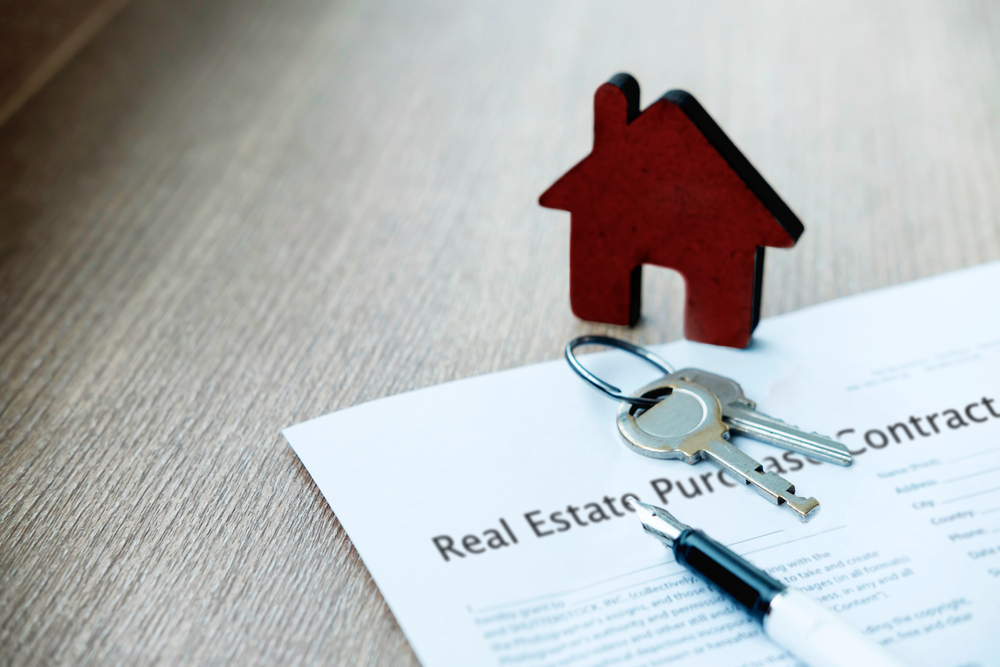 keys to a house on top of real estate transaction papers